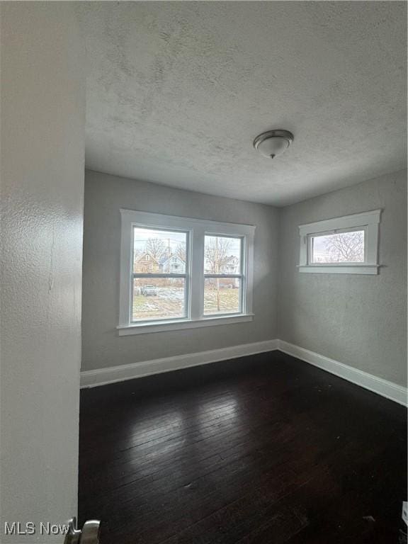 unfurnished room featuring dark hardwood / wood-style flooring and a textured ceiling