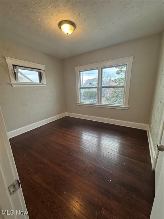 unfurnished room featuring dark wood-type flooring, a wealth of natural light, and a textured ceiling