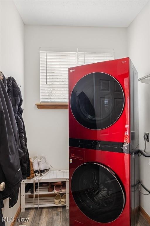 clothes washing area featuring wood-type flooring and stacked washer / dryer