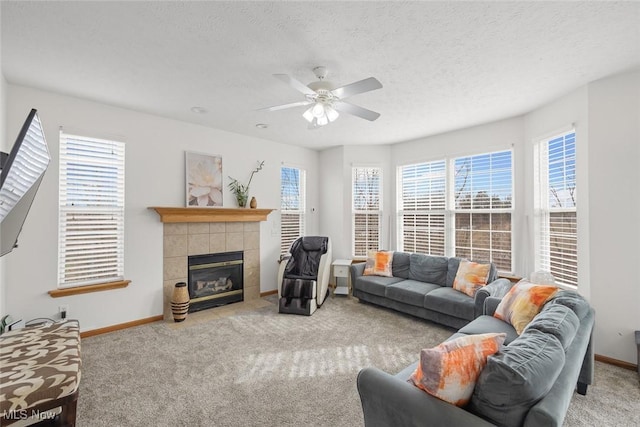 living room with ceiling fan, light carpet, a tile fireplace, and a textured ceiling