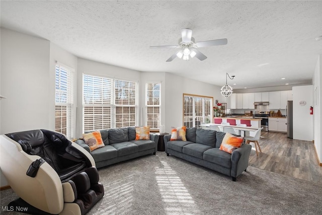 living room with hardwood / wood-style flooring, ceiling fan with notable chandelier, and a textured ceiling