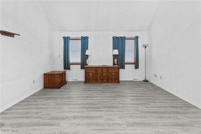 unfurnished bedroom featuring vaulted ceiling and light hardwood / wood-style floors