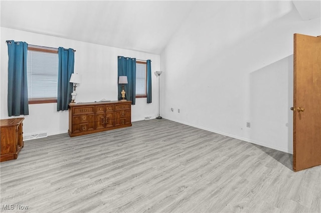 unfurnished bedroom featuring lofted ceiling and light hardwood / wood-style floors