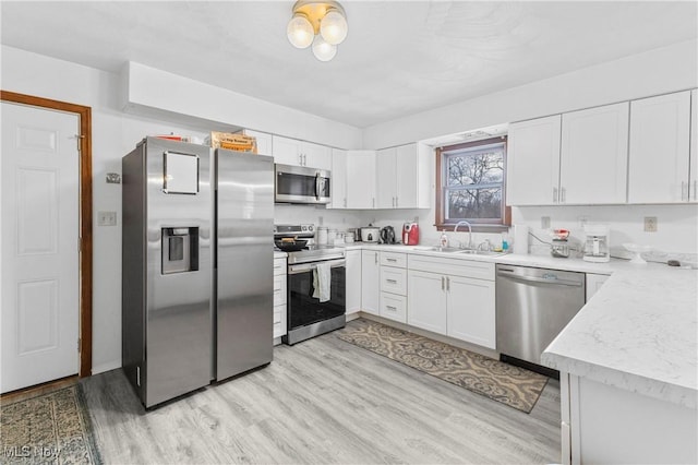 kitchen featuring white cabinetry, stainless steel appliances, sink, and light hardwood / wood-style flooring