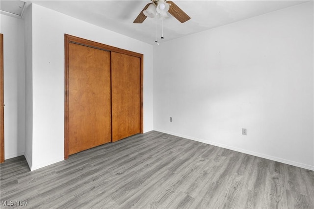 unfurnished bedroom with ceiling fan, a closet, and light wood-type flooring