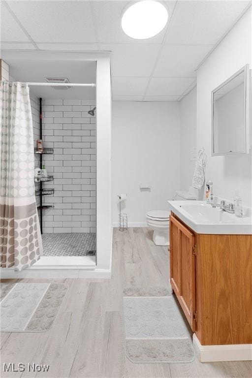 bathroom featuring hardwood / wood-style floors, curtained shower, vanity, toilet, and a drop ceiling