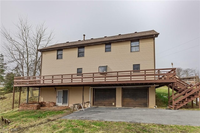 rear view of property featuring a garage, a deck, and a patio area