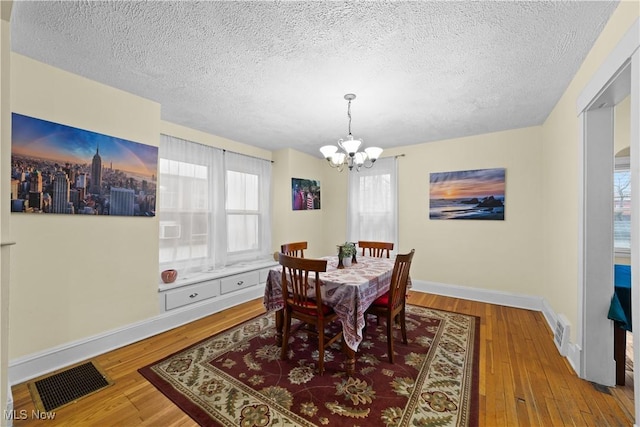 dining room with hardwood / wood-style floors, a notable chandelier, and a textured ceiling