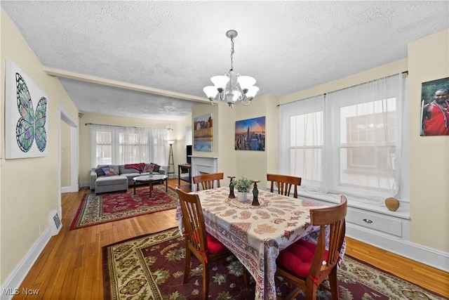 dining room with hardwood / wood-style floors, a textured ceiling, and a chandelier