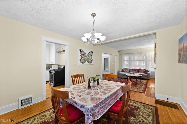 dining area featuring an inviting chandelier, hardwood / wood-style floors, and a textured ceiling