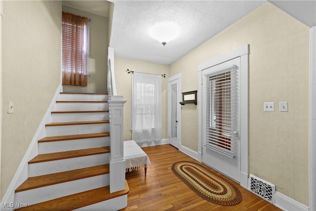 foyer entrance with a textured ceiling and light hardwood / wood-style flooring