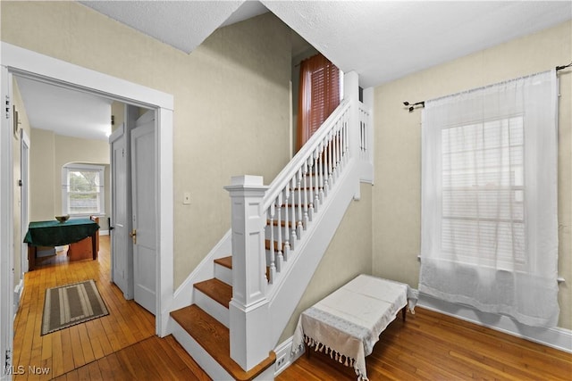 stairs with wood-type flooring and a textured ceiling