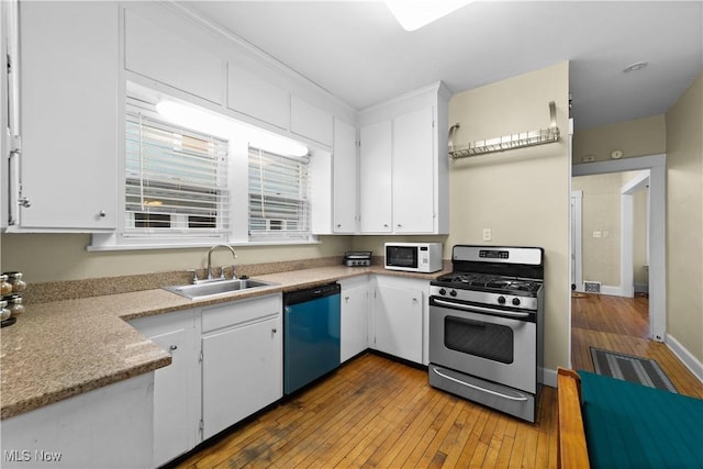 kitchen with stainless steel appliances, sink, hardwood / wood-style floors, and white cabinets