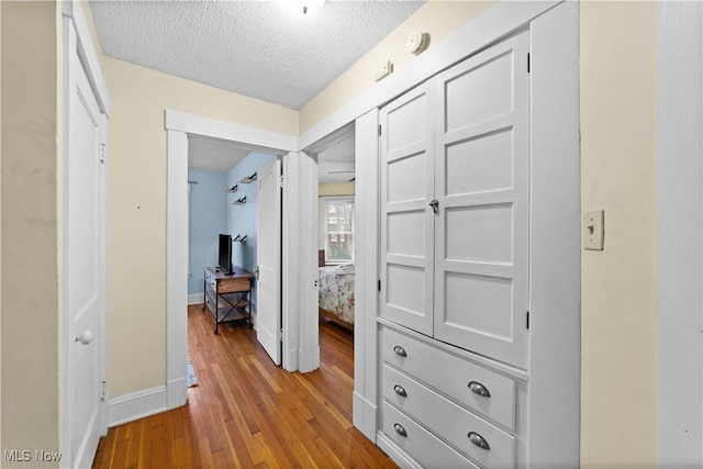 hall featuring light hardwood / wood-style flooring and a textured ceiling