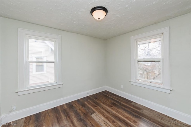 spare room with dark hardwood / wood-style floors and a textured ceiling