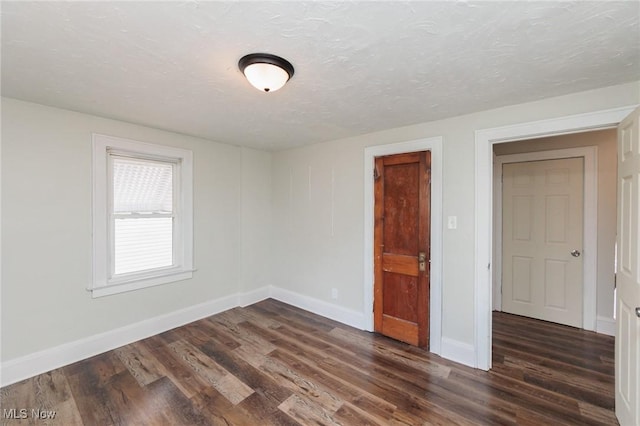 spare room featuring dark hardwood / wood-style floors and a textured ceiling