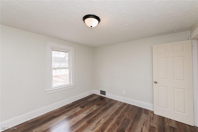 spare room with dark wood-type flooring and a textured ceiling