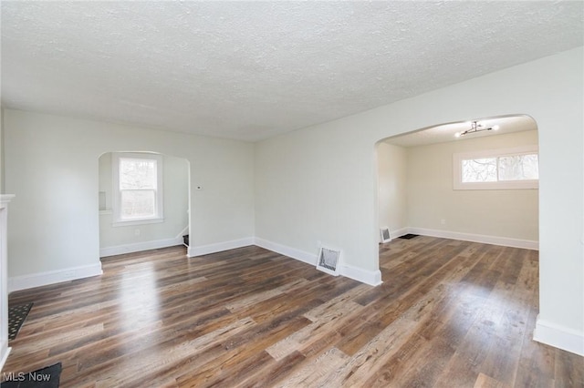 spare room with a healthy amount of sunlight, a textured ceiling, and dark hardwood / wood-style flooring