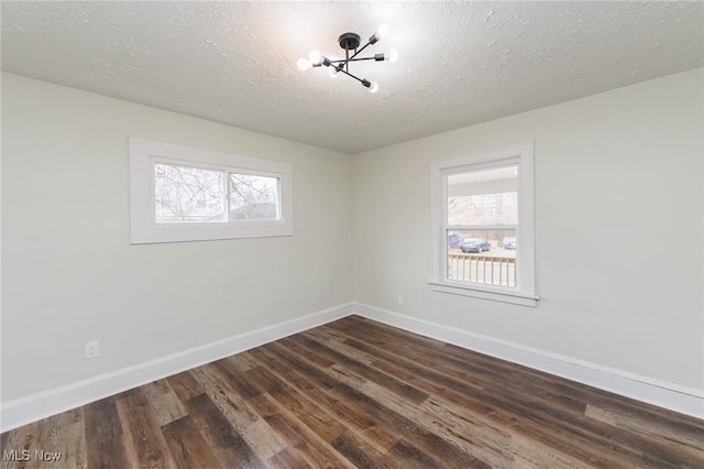 unfurnished room with dark wood-type flooring and a textured ceiling