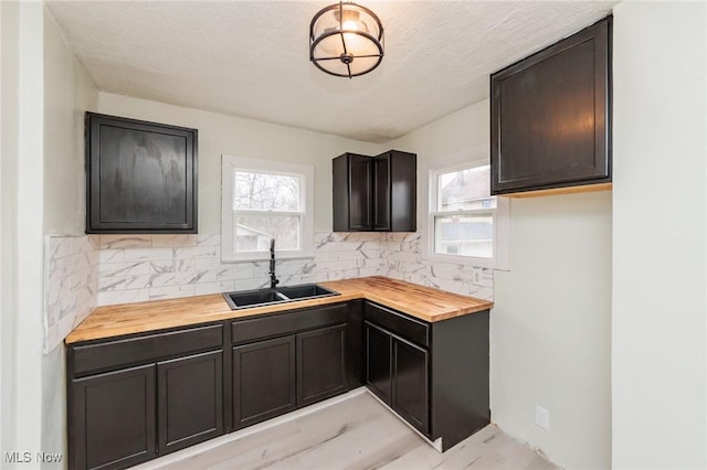 kitchen featuring wooden counters, sink, decorative backsplash, and a textured ceiling