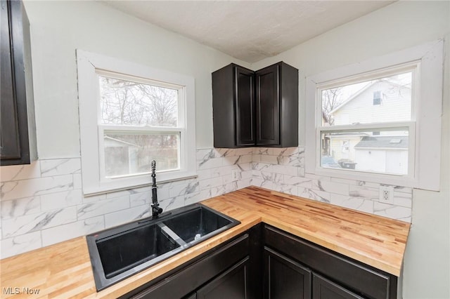 kitchen featuring backsplash, sink, butcher block countertops, and a wealth of natural light