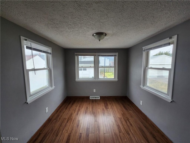 unfurnished room featuring dark wood-type flooring and a textured ceiling