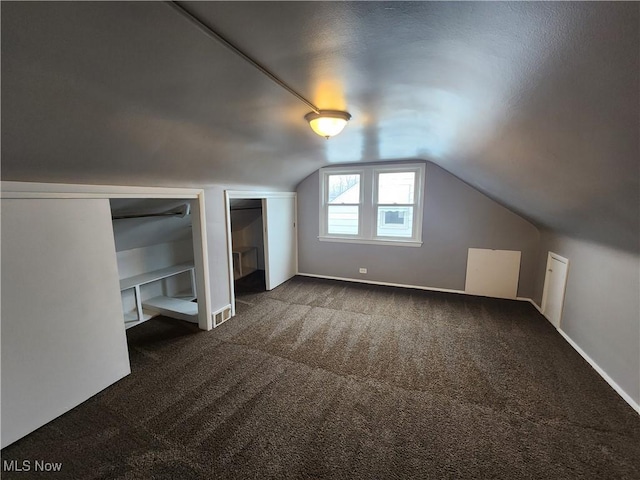 additional living space featuring dark carpet and vaulted ceiling