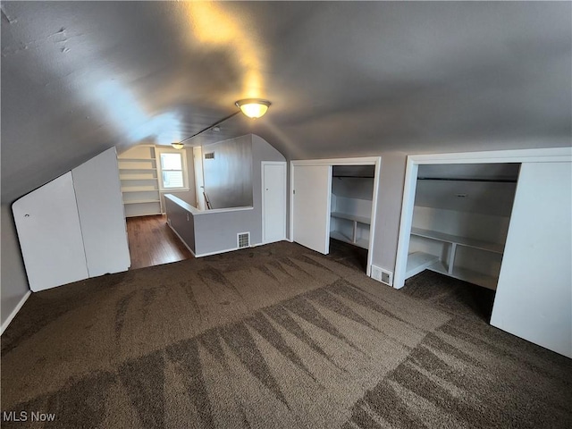 bonus room with dark carpet and vaulted ceiling