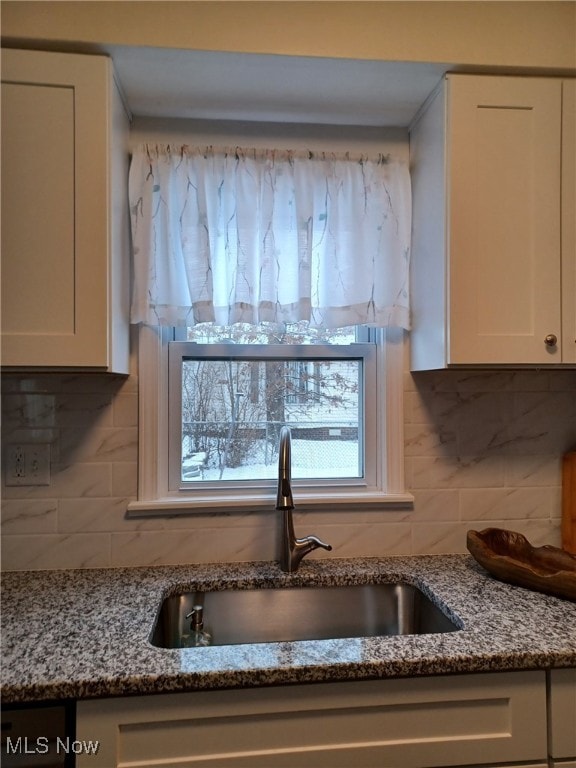 room details featuring sink, white cabinets, and stone countertops