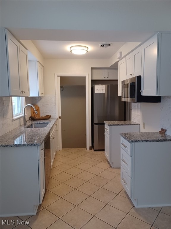 kitchen with stainless steel appliances, white cabinetry, sink, and backsplash