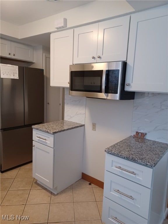 kitchen featuring white cabinetry, light tile patterned floors, tasteful backsplash, and stainless steel appliances