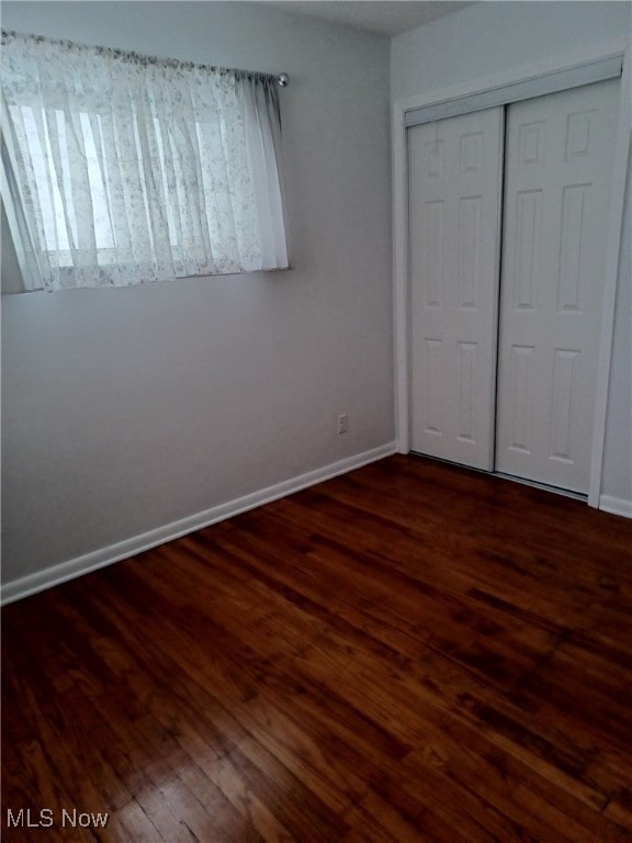 unfurnished bedroom featuring dark hardwood / wood-style floors and a closet