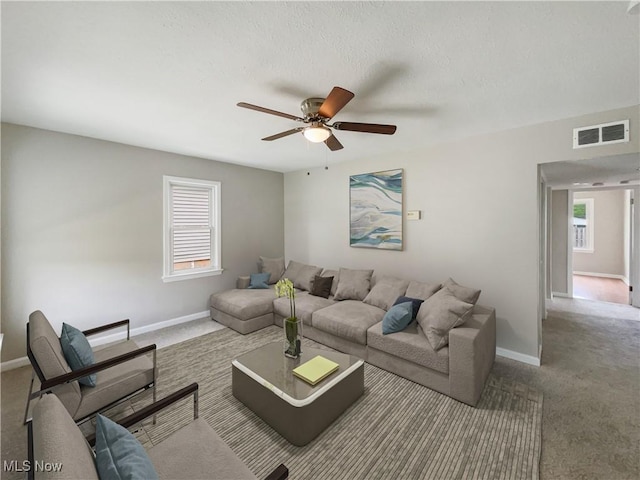 carpeted living room with a textured ceiling and ceiling fan