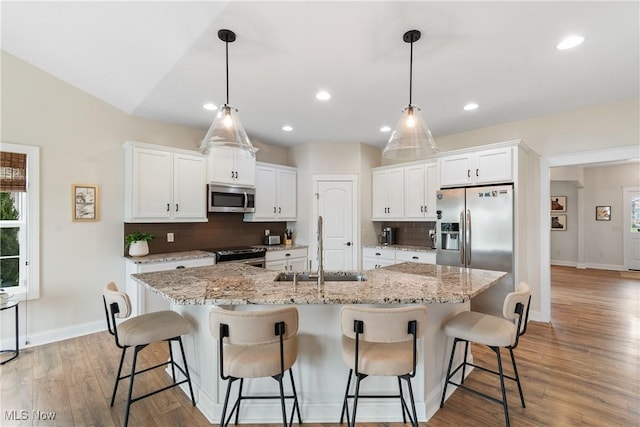 kitchen featuring white cabinetry, stainless steel appliances, a large island, and sink