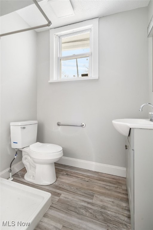 bathroom featuring vanity, hardwood / wood-style flooring, a textured ceiling, and toilet