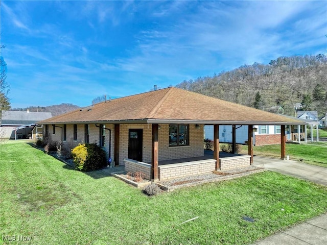 ranch-style house featuring an attached carport, brick siding, driveway, roof with shingles, and a front lawn