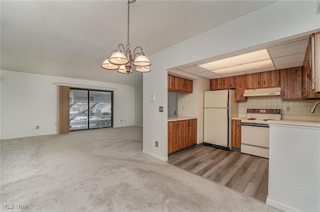 kitchen featuring decorative backsplash, hanging light fixtures, a notable chandelier, light carpet, and white appliances