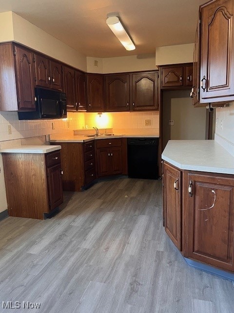 kitchen with decorative backsplash, light hardwood / wood-style flooring, black appliances, and dark brown cabinets