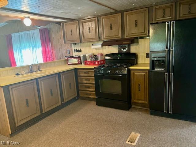 kitchen with sink, light carpet, and black appliances