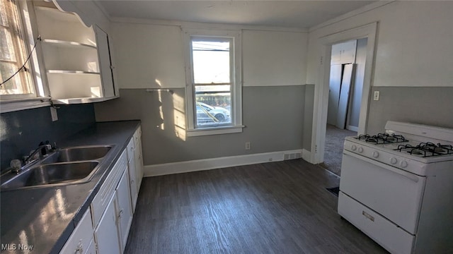 kitchen featuring dark wood-type flooring, white gas range, sink, and white cabinets