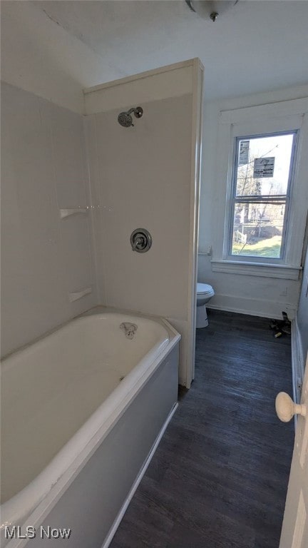 bathroom with wood-type flooring, bathing tub / shower combination, and toilet