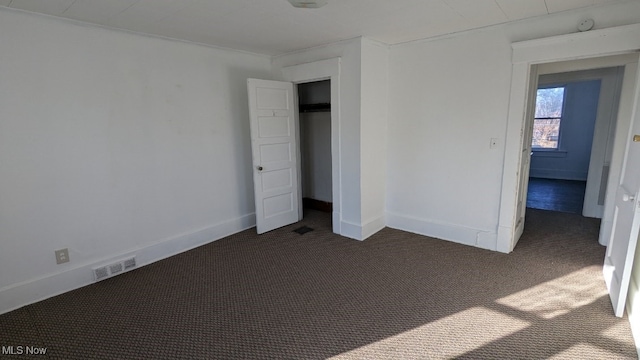 unfurnished bedroom featuring dark colored carpet and a closet