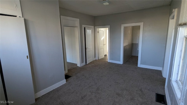 unfurnished bedroom with a closet and dark colored carpet