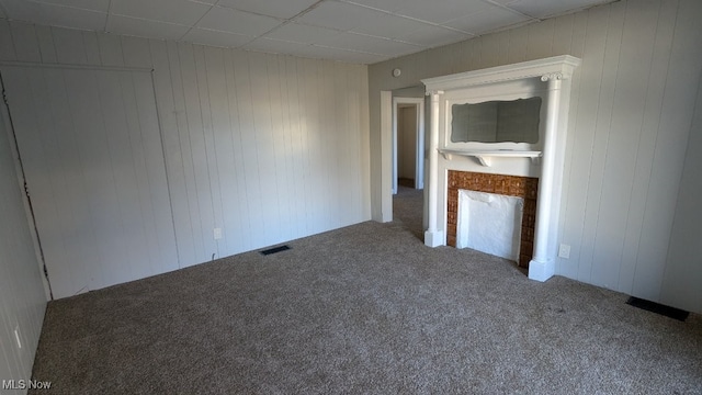 carpeted empty room featuring a fireplace and a paneled ceiling