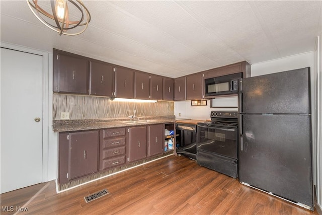 kitchen with decorative light fixtures, sink, dark wood-type flooring, black appliances, and dark brown cabinets