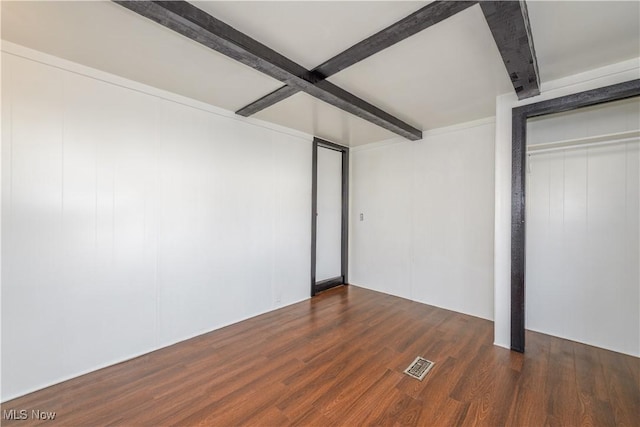 unfurnished bedroom with beam ceiling and dark hardwood / wood-style floors