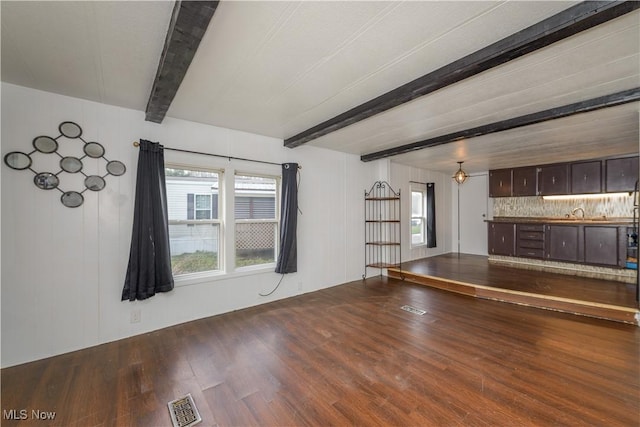 unfurnished living room featuring beam ceiling and wood-type flooring