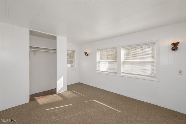 unfurnished bedroom with dark colored carpet and a closet