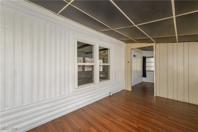 unfurnished room with dark wood-type flooring and wood walls