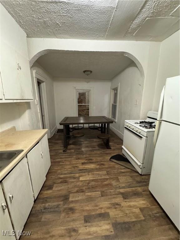 kitchen featuring white appliances, a textured ceiling, dark hardwood / wood-style floors, and white cabinets